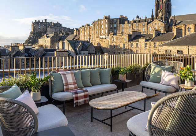 Spacious rooftop area at Virgin Hotels Edinburgh with modern furnishings overlooking Edinburgh Castle.