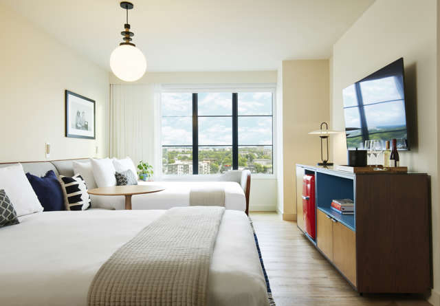 Spacious double queen chamber at Virgin Hotels Nashville with two plush beds, modern decor, and ambient lighting, offering a comfortable, stylish stay.