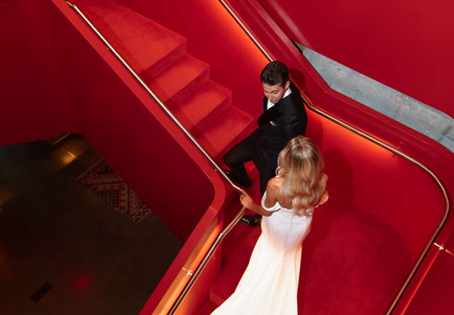 Bride and groom walking up a grand staircase at Virgin Hotels New York, capturing a romantic moment in an elegant setting.