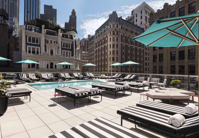 Poolside terrace at Virgin Hotels New York with modern lounge seating, shaded cabanas and offering a chic outdoor relaxation space.