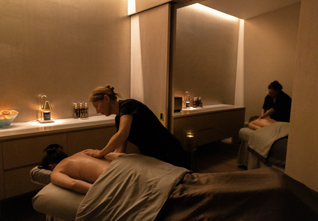 Relaxing spa experience with two massage therapists giving soothing treatments in a calm, dimly lit environment.